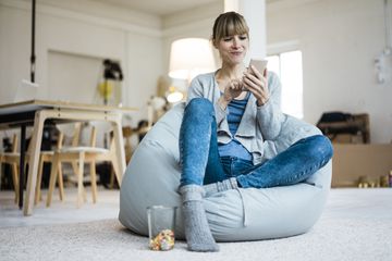 女人坐在豆袋椅使用手机。