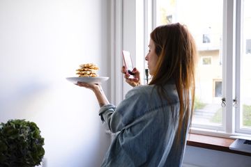 女人把一盘的照片与她的iPhone华夫饼干