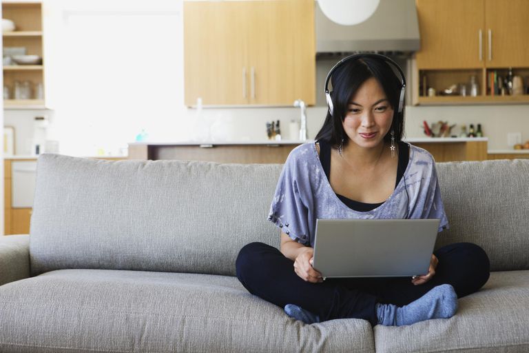 亚洲女人在沙发上用笔记本电脑通过VoIP聊天